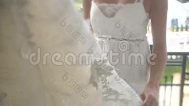 美丽美丽的金发新娘正在享受她的<strong>时尚婚纱</strong>挂在衣架上。
